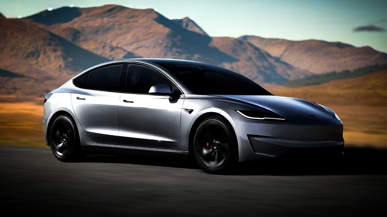 Tesla model 3 in grey driving down a road with mountains and sand.