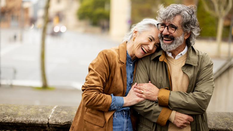 An older couple smiling together in an outdoor setting.