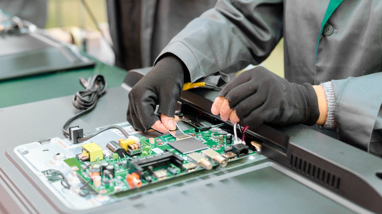 An electrician repairing the internal components of a TV