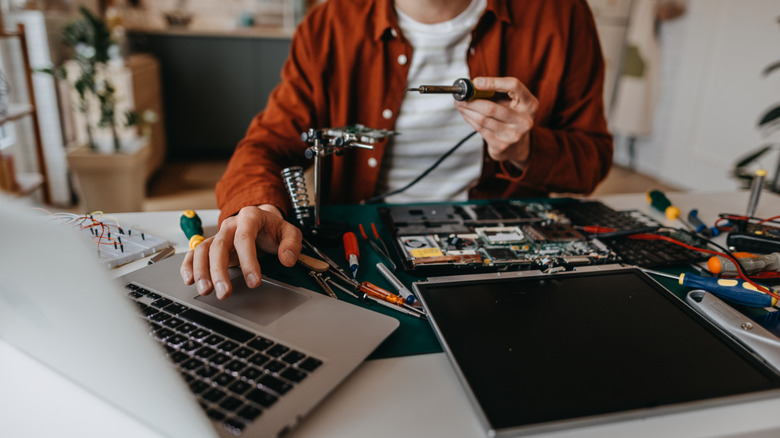 A man repairs his electronics by following online instructions