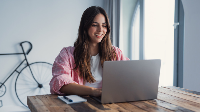 A women sitting at a table and typing on a laptop
