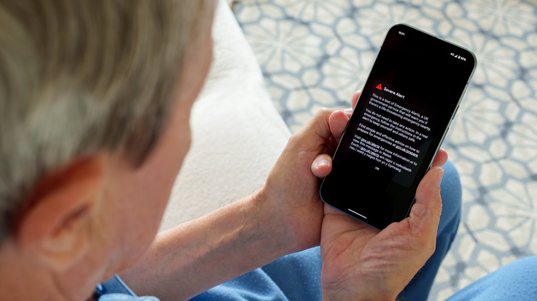 A man holding an iPhone showing a Severe Alert.