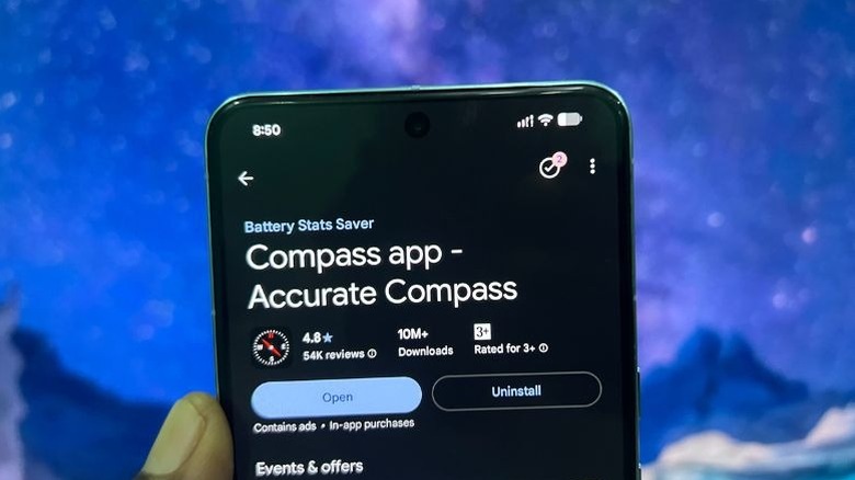 Hand holding a smartphone showing Accurate Compass play Store listing