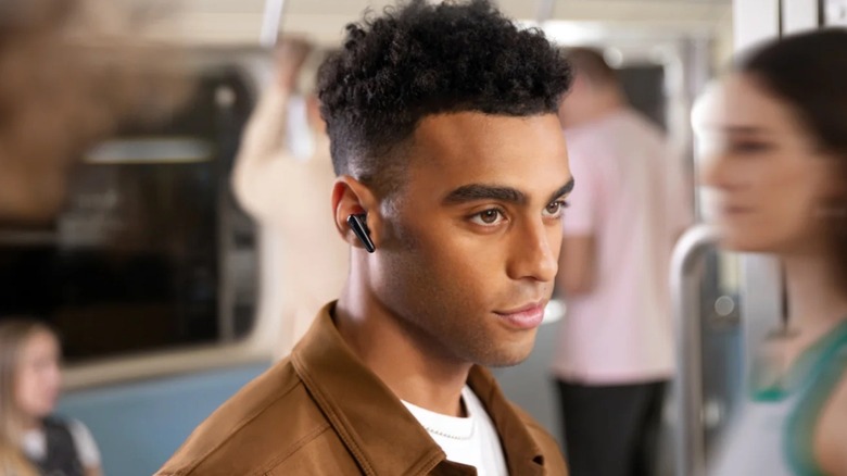 Man wearing Soundcore's earbuds on a subway