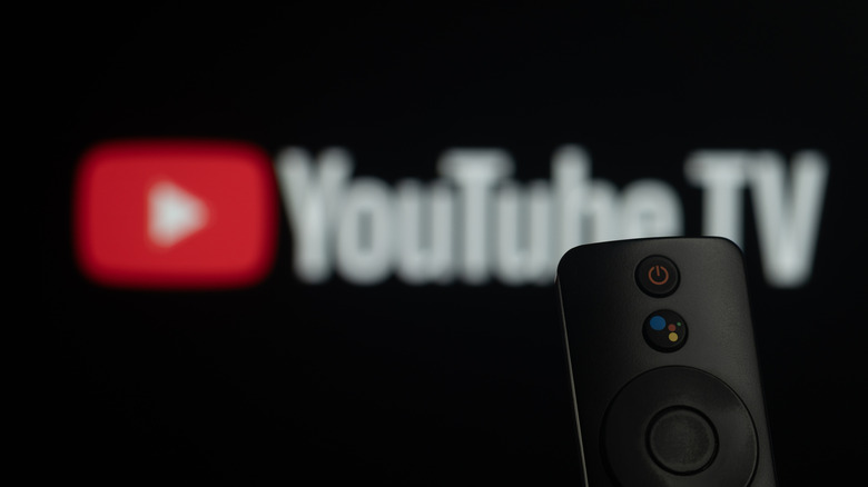 A TV remote in the foreground with the YouTube TV logo blurred in the background