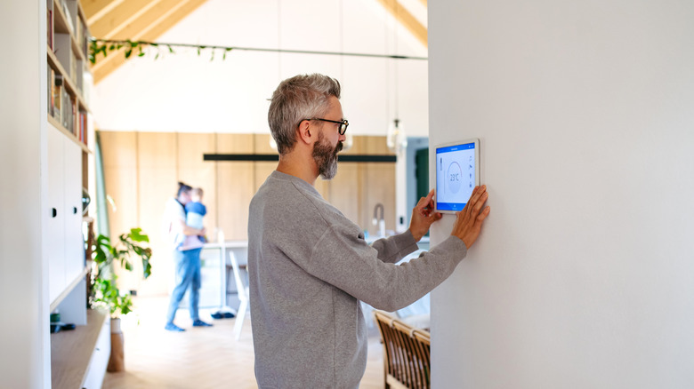 A man placing a tablet into a wall mount to be used as a smart home kiosk