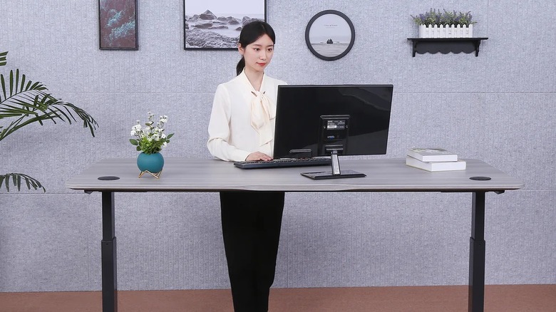 Woman using the ApexDesk Elite Series Height Adjustable Desk while working on monitor