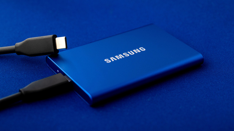 Samsung portable SSD T7 with two connected USB Type C cables on a vibrant blue surface