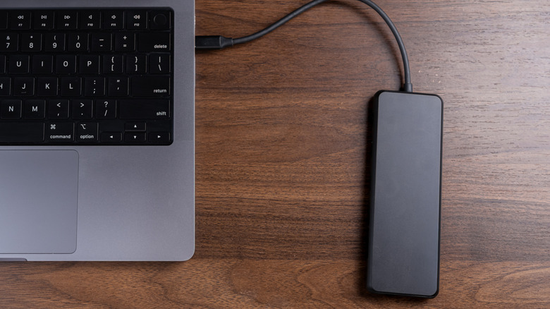 Overhead shot of a modern laptop linked to a portable external drive on a wooden desk,