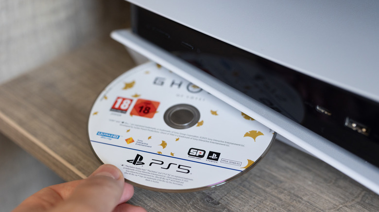 A person inserting a disc into a PlayStation 5 game console