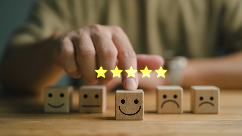Five-star customer satisfaction rating concept showing wooden dice with happy and sad faces