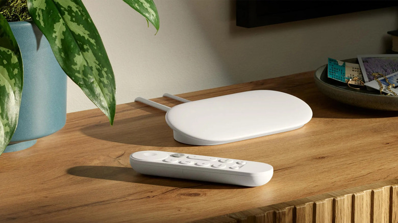 White Google TV Streamer 4K placed on a wooden table alongside a remote