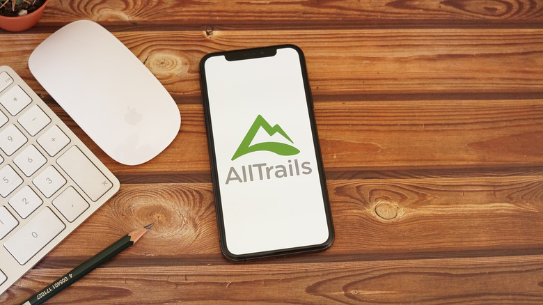The AllTrails app on an iPhone lying on a wooden table