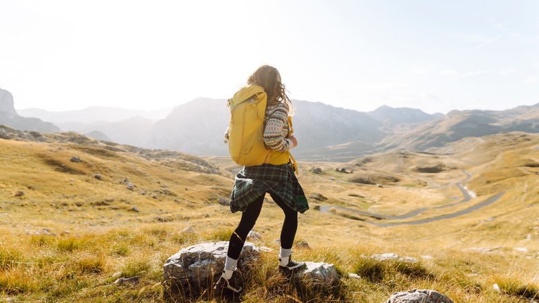 A woman hiking alone in the hills with a yellow backpack