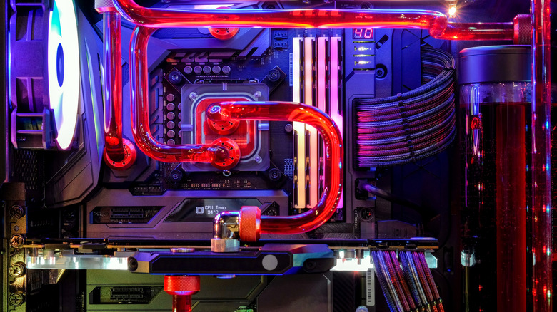 Custom liquid cooling loop inside a gaming PC with red tubing, RGB lighting, and a visible reservoir.