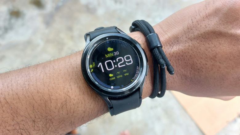A black Samsung Galaxy 4 Classic being worn on an individual's left wrist, the wearer seems to be standing outside
