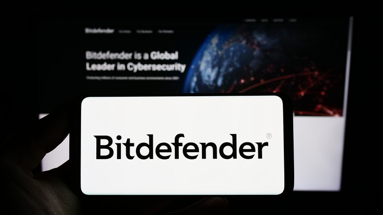 Bitdefender logo on a smartphone in front of the Bitdefender website.