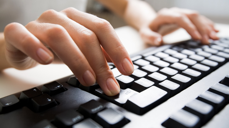 A person typing on a computer keyboard.