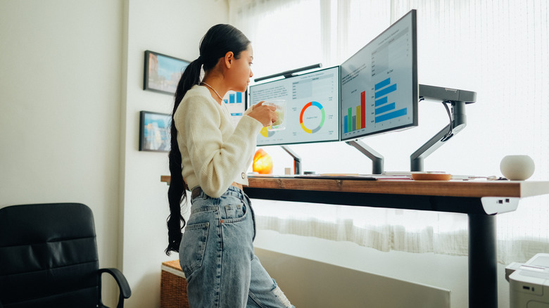 An office worker using dual monitors on articulated stands.