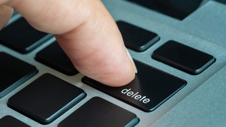 A person pressing the Delete key on a keyboard.