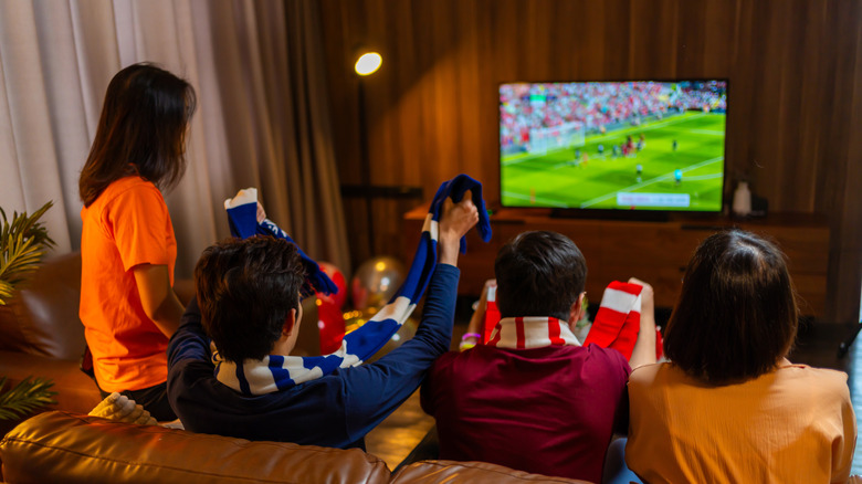 A group of people watching soccer on TV