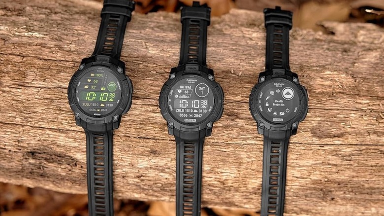 Garmin Instinct 3 Solar Tactical Edition smartwatch for outdoors, all three models on a log.