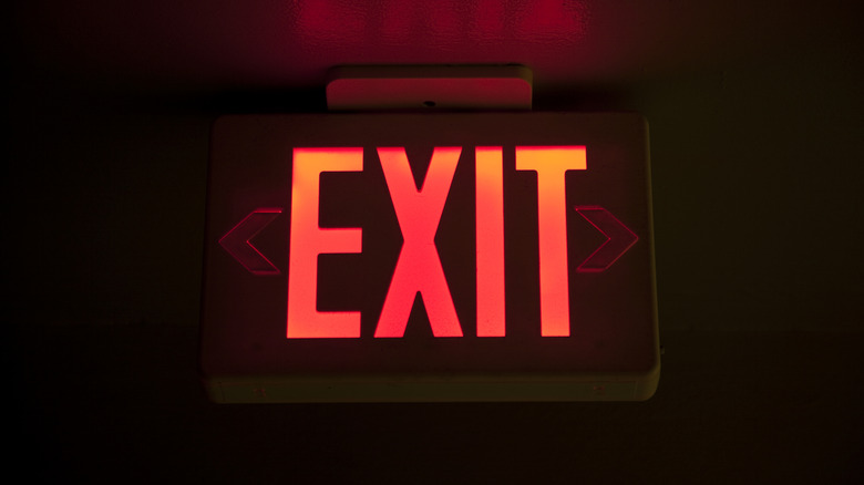 Red illuminated exit sign glowing in a dark room.