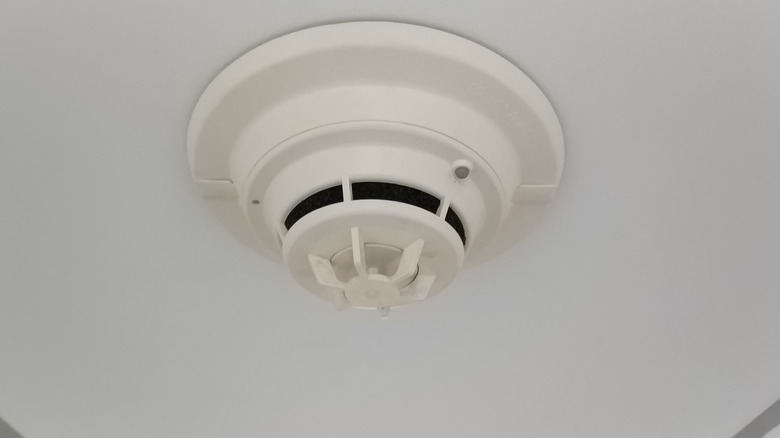 Ceiling-mounted smoke detector on a white ceiling.