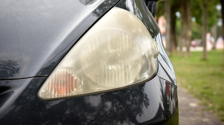 Cloudy car headlight with oxidized plastic lens shown in close-up.