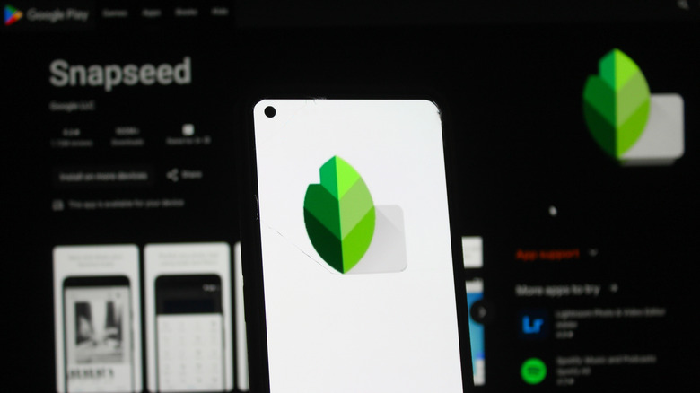 Snapseed logo on phone screen held in front of laptop
