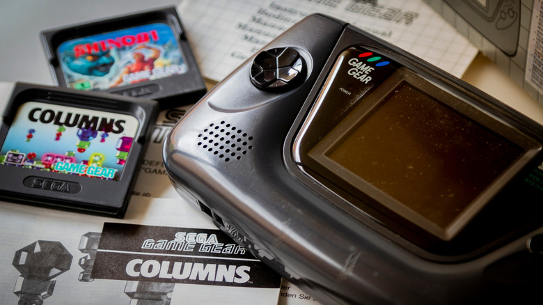 Close up of the Sega Game Gear handheld console on a desk with game cartridges.