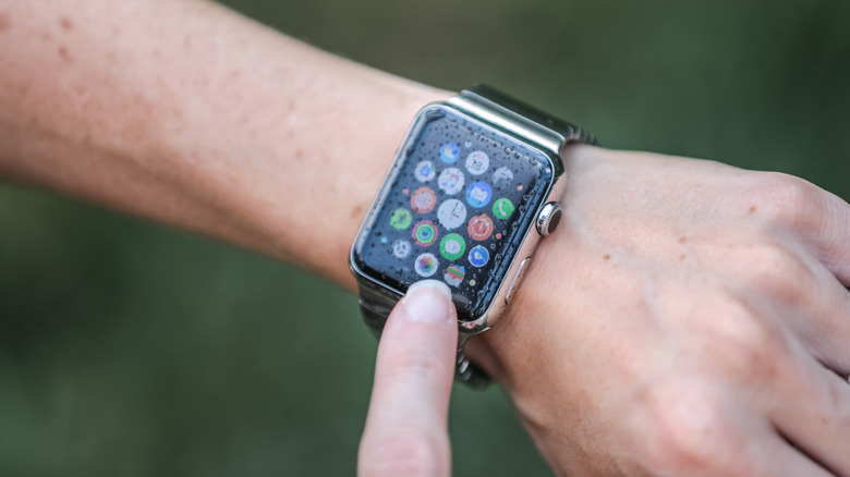 A wrist showing an Apple Watch with apps and a wet screen.