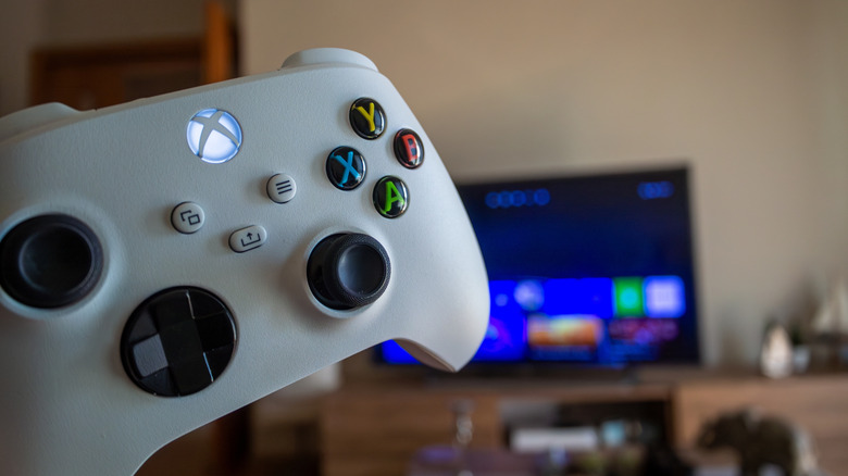 An Xbox game controller in front of a TV.