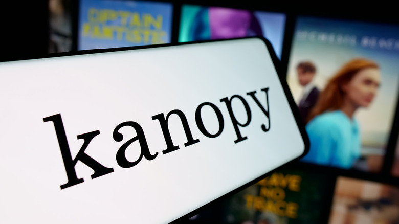Kanopy logo on a smartphone with a TV running the service in the background
