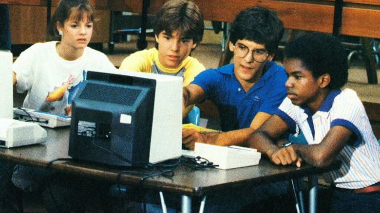 Several kids sitting around a 1980s computer