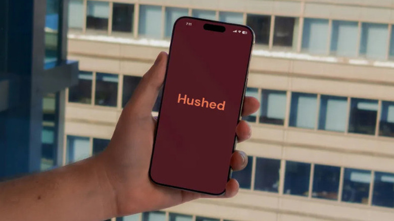 Hand holding a smartphone with Hushed app logo displayed