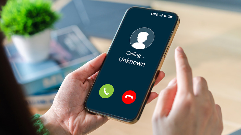 Person holding a phone with an incoming call from unknown number