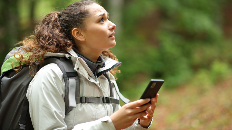Worried lost hiker trying to use their phone in the woods