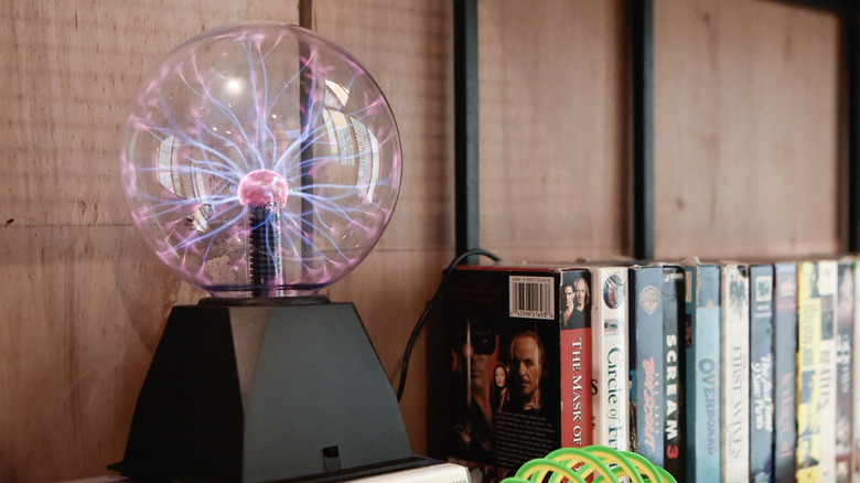 Plasma ball on bookshelf next to VHS tapes