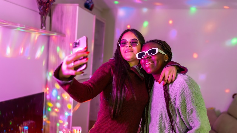Two people taking a selfie with disco lights in the background