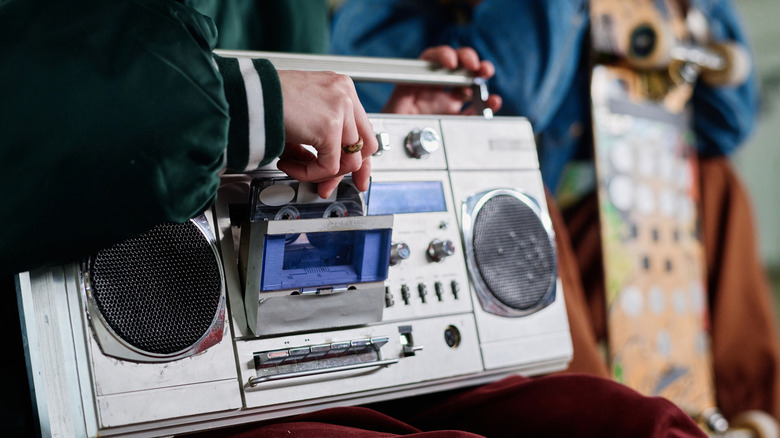 Closeup of a person inserting a cassette into a retro boombox