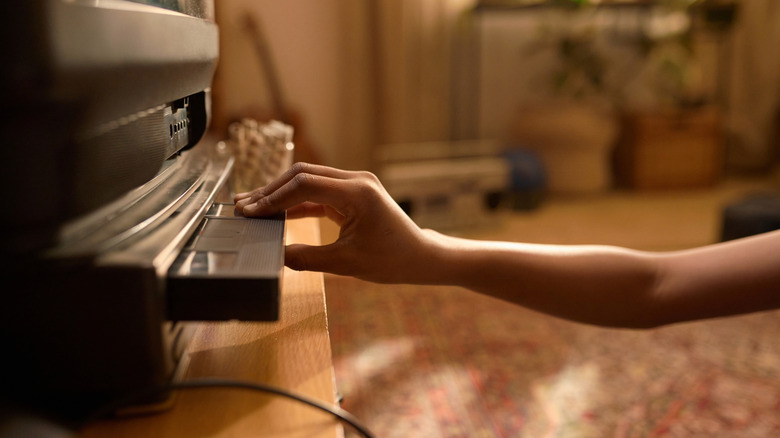 Hand inserting a VHS tape into a VCR