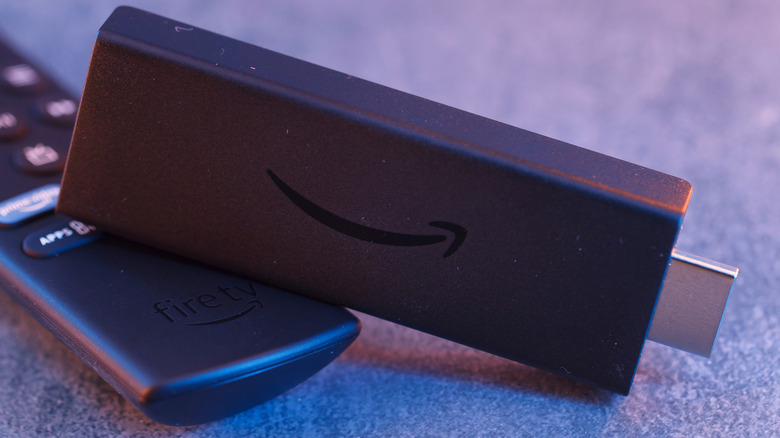 A closeup of a black Amazon Fire TV streaming stick sitting on top of its black remote