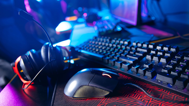 A headset, computer mouse, and computer keyboard sitting on a desk