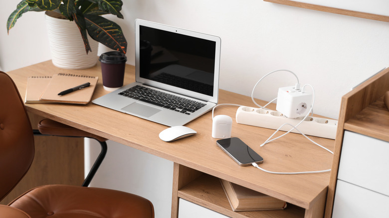 Close up shot of a desk with devices, a power strip, notebooks, and other gadgets.