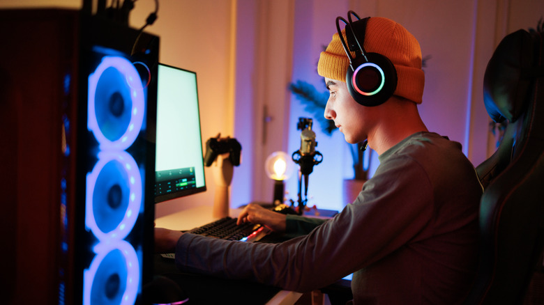 Person wearing a headset while gaming at a desktop PC with RGB lighting.