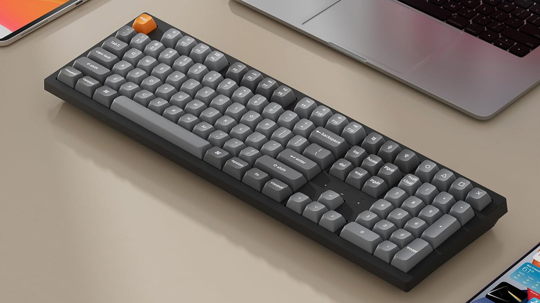 Keychron K10 Max mechanical keyboard on a desk beside a laptop.