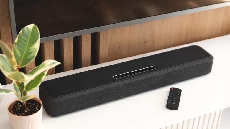A soundbar placed below a TV on a piece of furniture.