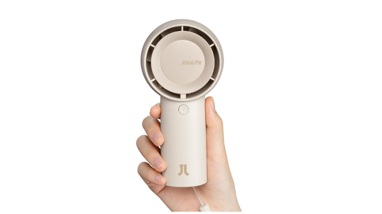 A portable fan placed on table with its box and charging cables