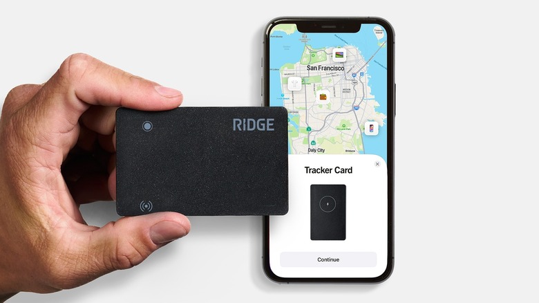 A person holding the Ridge Wallet Tracker Card in their hand with an iPhone on the side